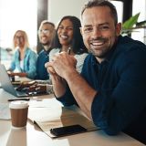 Vier lächelnde Kolleginnen und Kollegen sitzen am Tisch