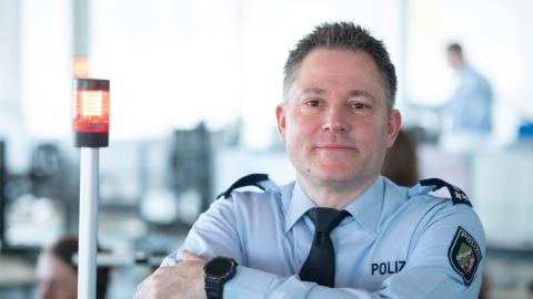 Service group leader Ralf Bojack leans against the side of a structure in the control center of Cologne Police Headquarters.